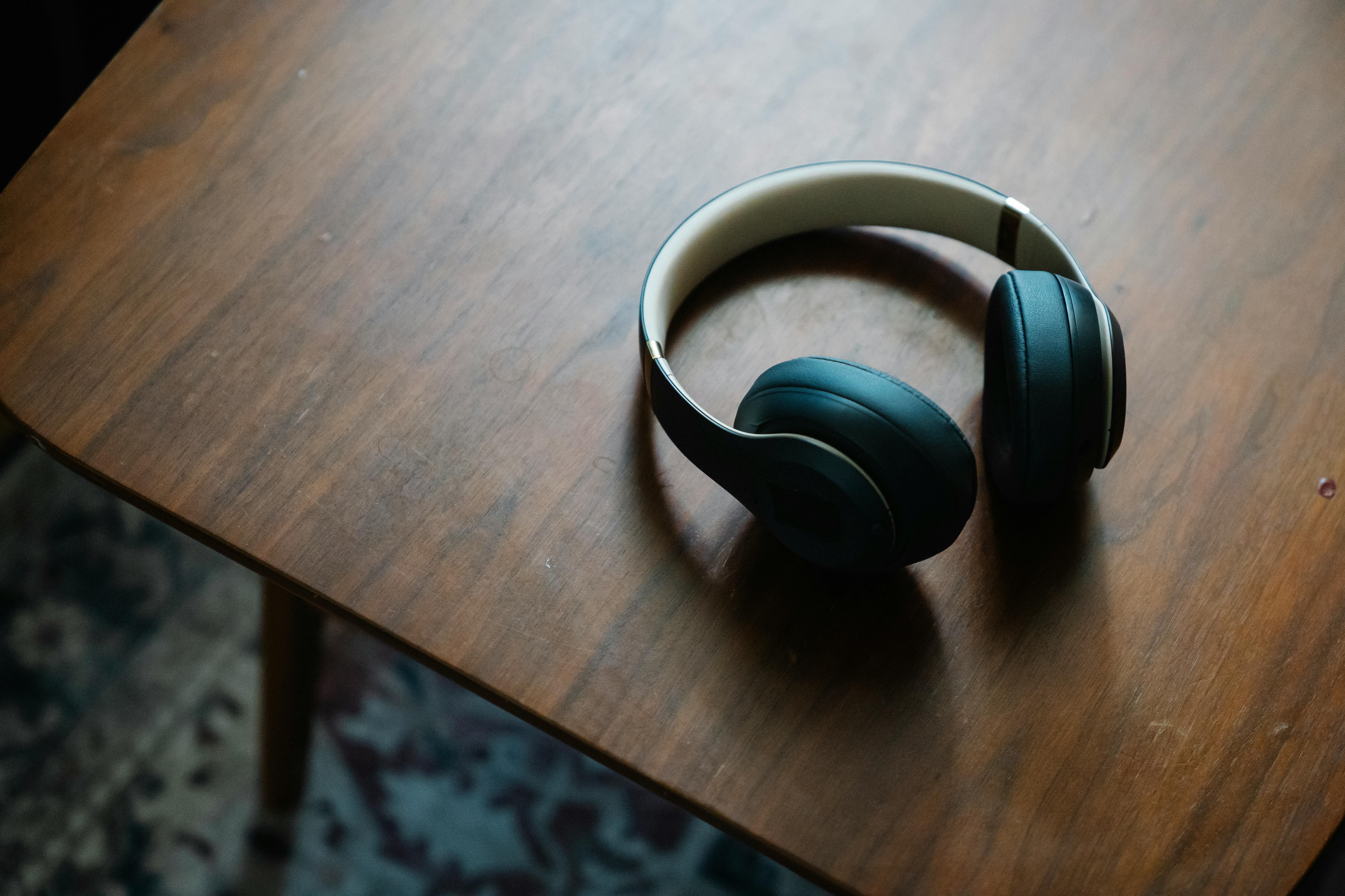 An image of a pair of black headphones on a wooden side