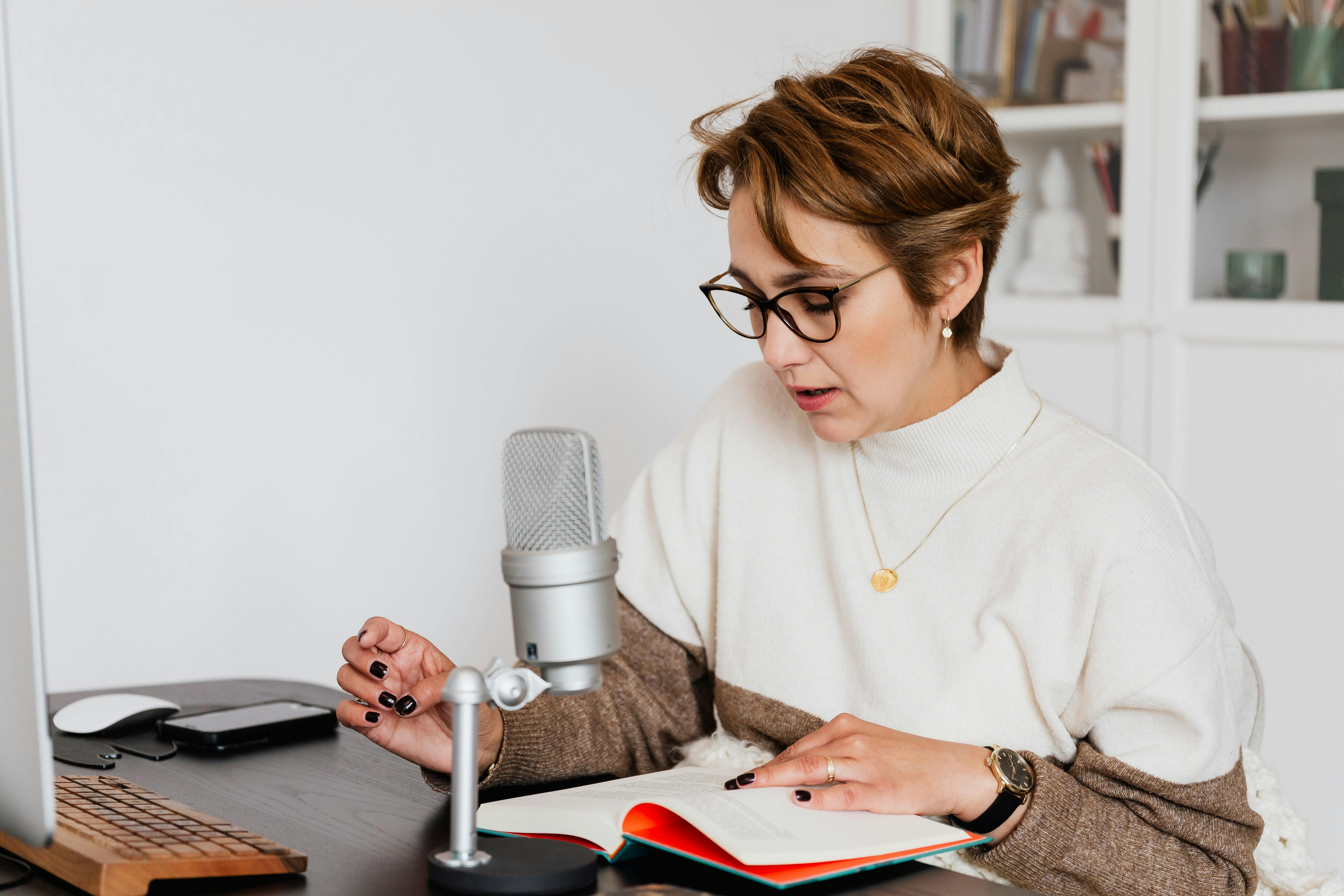 A woman sitting in front of a microphone narrating a book