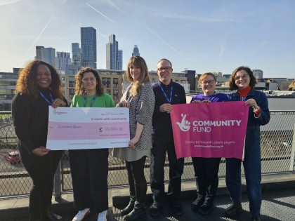 Listening Books staff members outside, and displaying a National Lottery banner, and large cheque.